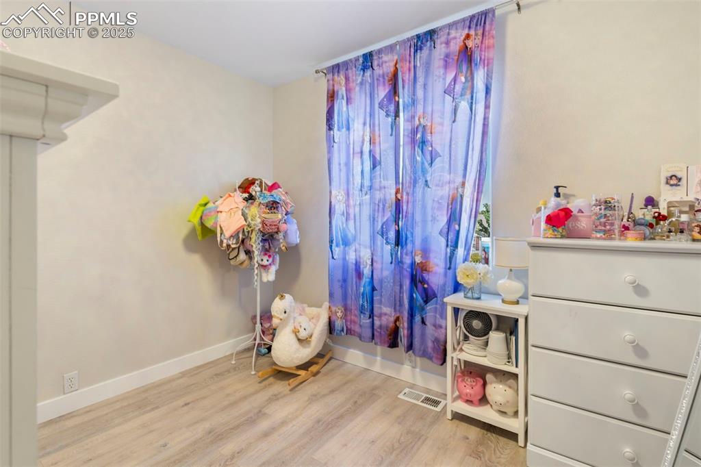 Image 19 of 25: Bedroom with light wood-style flooring and baseboards