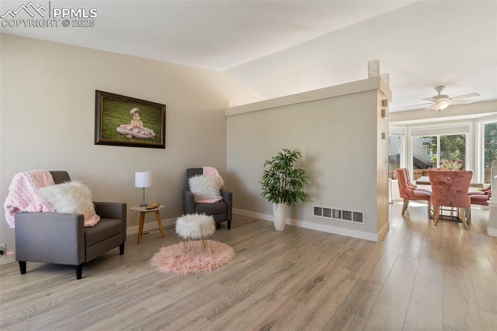 Image 3 of 25: Living area featuring light wood finished floors, ceiling fan, and vaulted