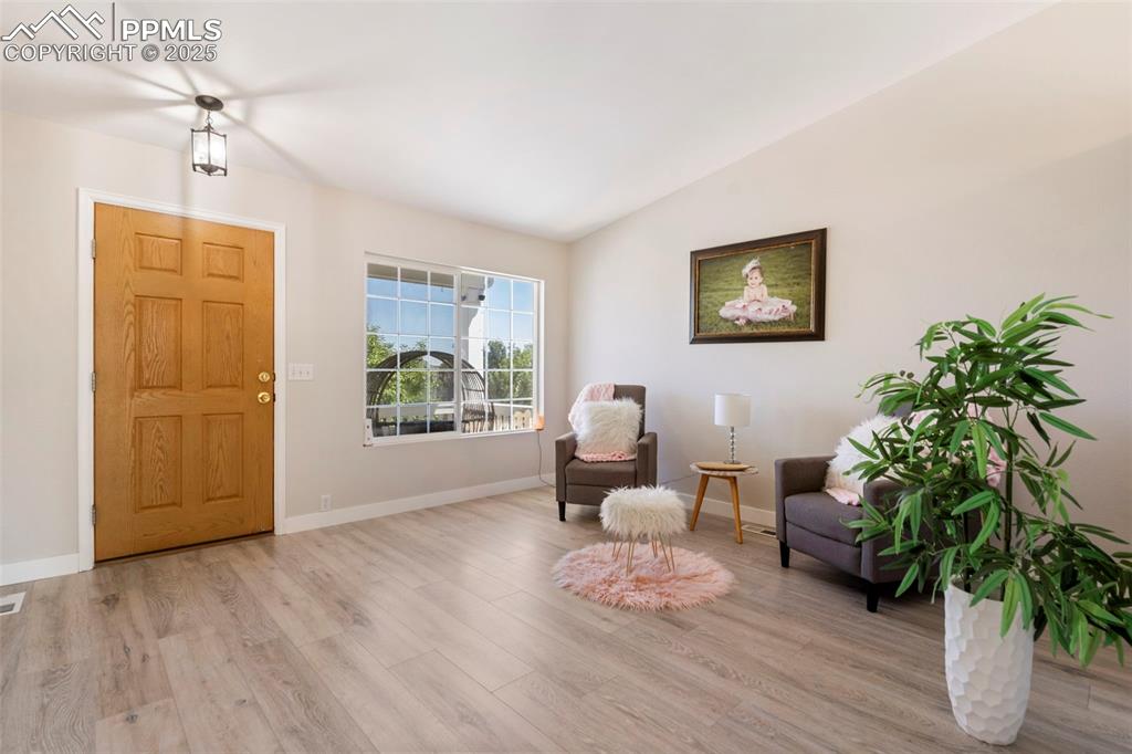 Image 4 of 25: Sitting room with light wood-style floors and lofted ceiling