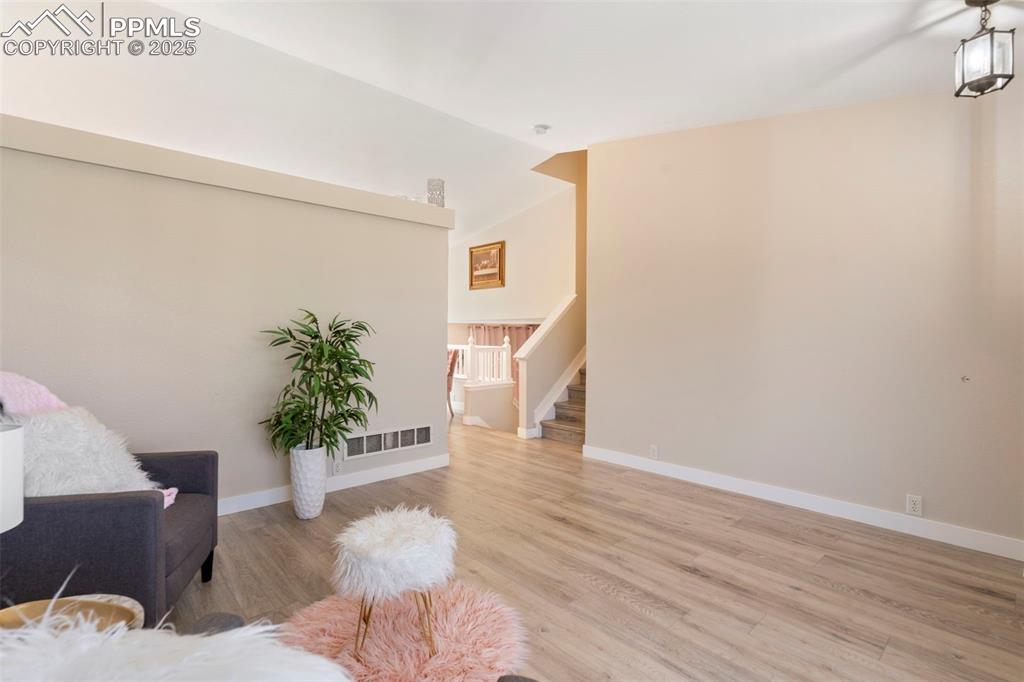 Image 5 of 25: Sitting room with light wood-style flooring, vaulted ceiling, and stairs