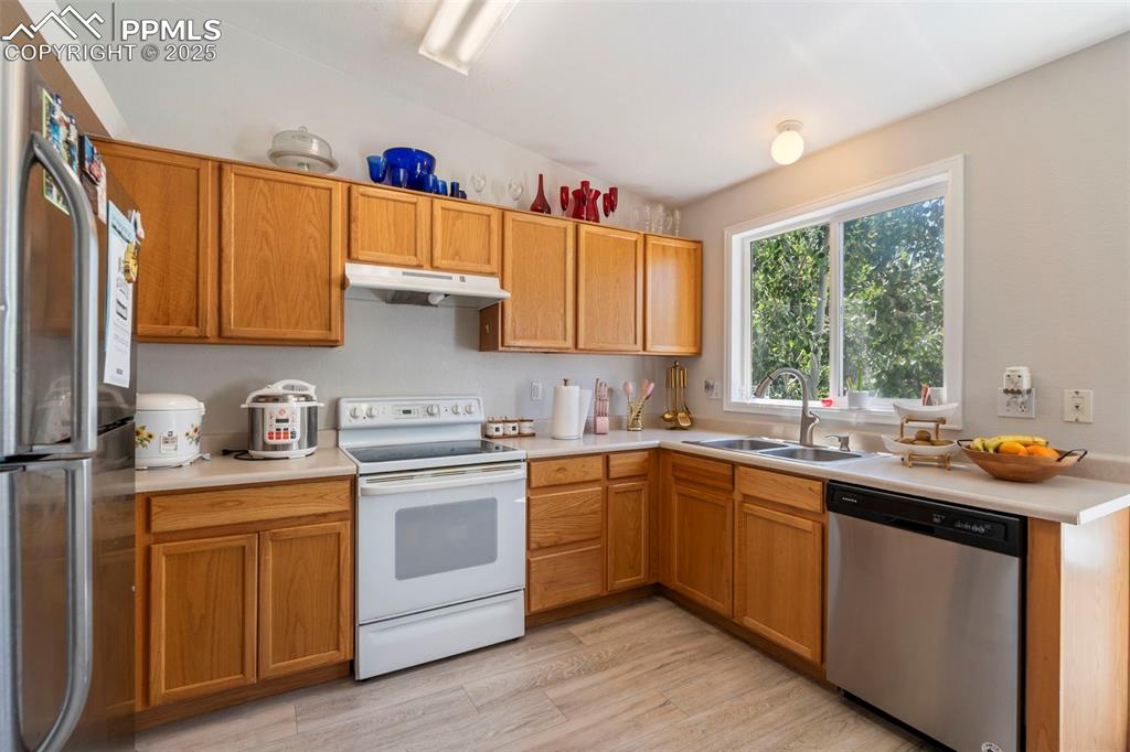 Image 7 of 25: Kitchen with appliances with stainless steel finishes, light countertops, l