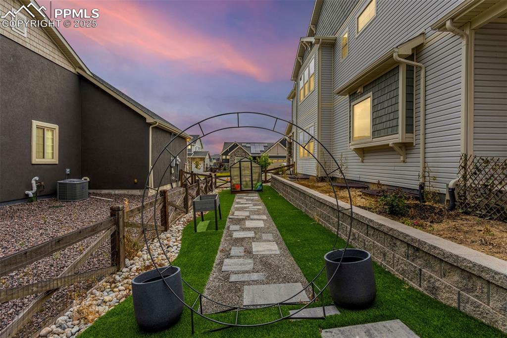 Image 32 of 34: Circular metal garden trellis is the entry to the custom walkway leading to