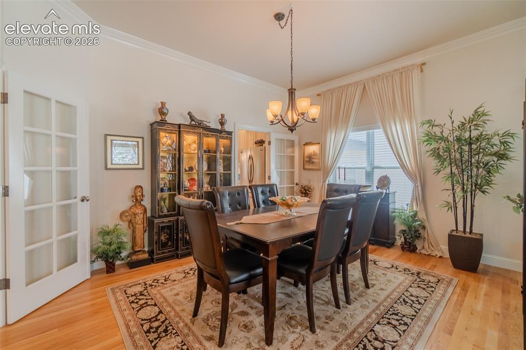 Image 11 of 48: Dining area featuring hardwood flooring, crown molding, a multi-light chand