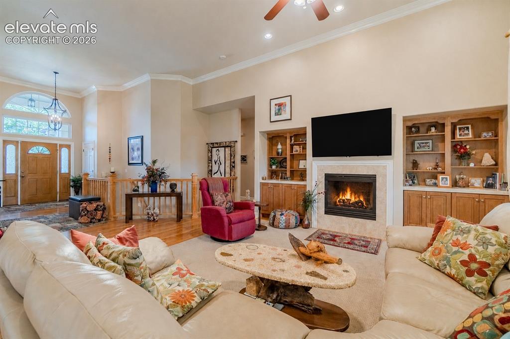 Image 12 of 47: Living area featuring a central fireplace with built-in shelving, vaulted c