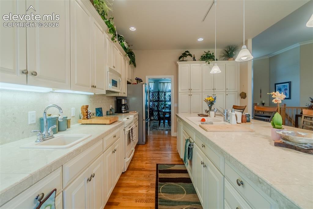 Image 17 of 48: Kitchen featuring two sinks, white cabinetry, granite countertops, recessed