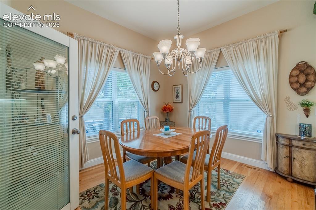 Image 18 of 48: Dining area featuring wood-finish flooring, a multi-light chandelier, and m
