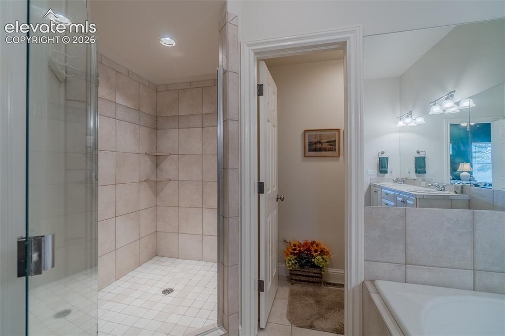 Image 19 of 47: Tile-surround shower with a glass enclosure, integrated shelving, door to t