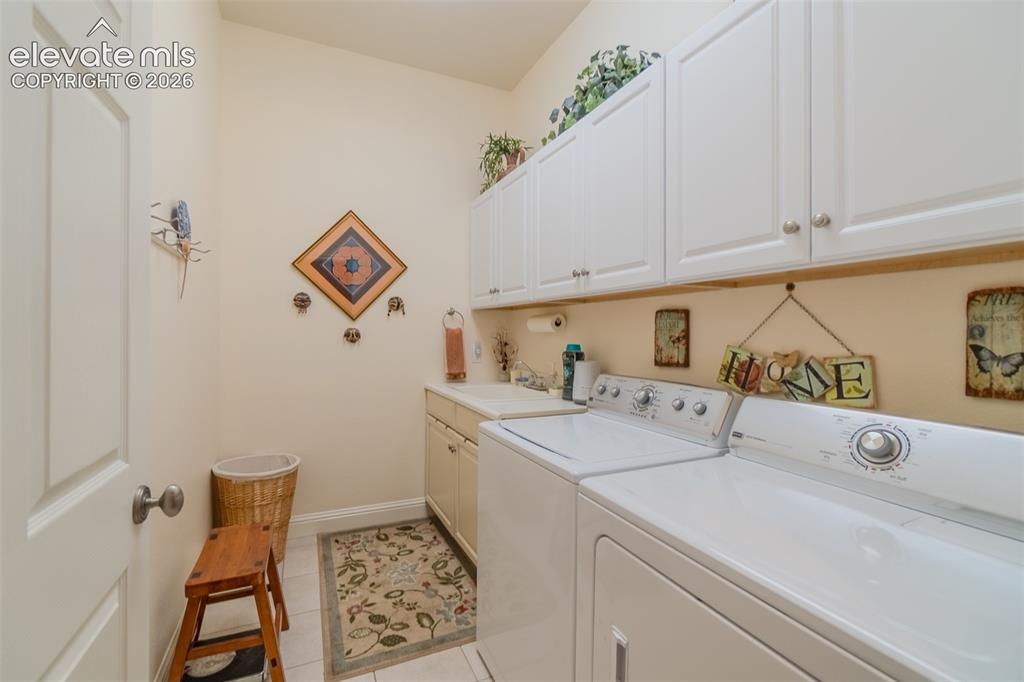 Image 22 of 47: Laundry space featuring white cabinetry, a built-in utility sink, and tile