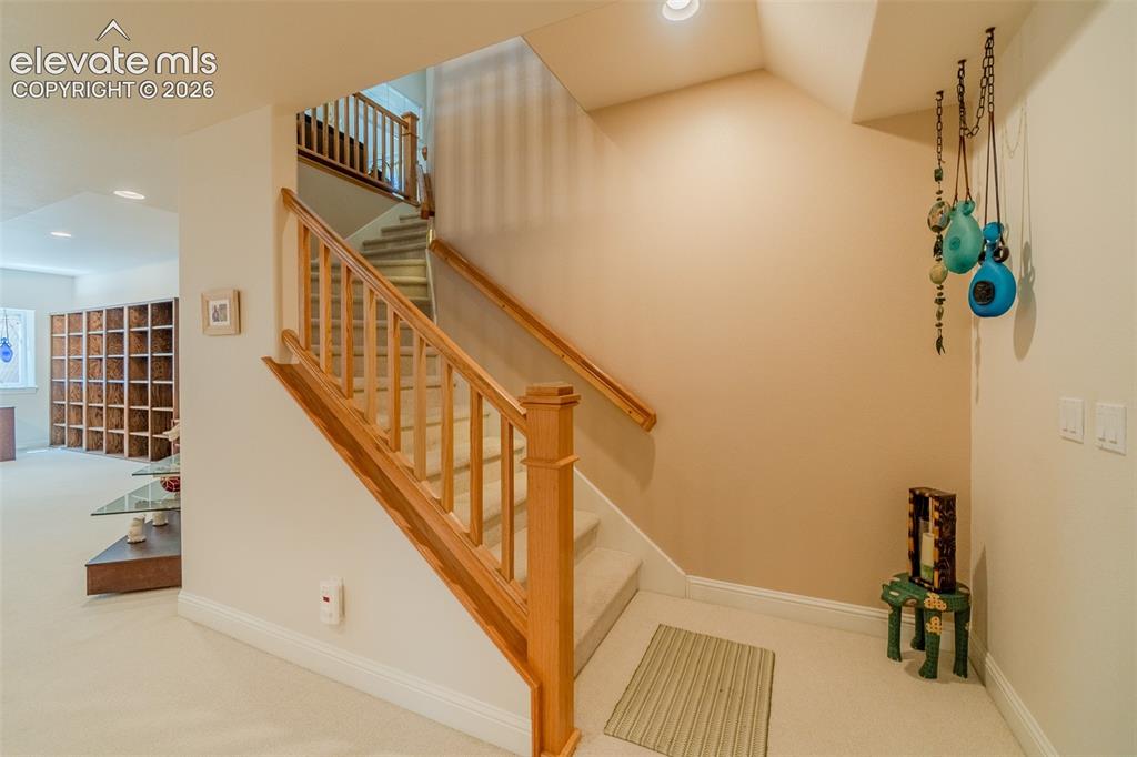 Image 25 of 47: Carpeted staircase with wood railings and balusters, featuring recessed lig