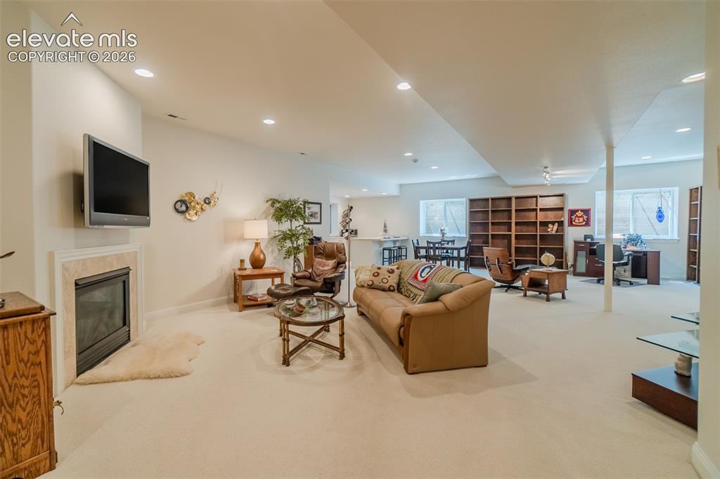 Image 26 of 47: Expansive lower-level space featuring a built-in fireplace with a stone sur