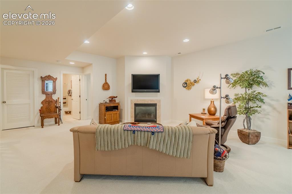 Image 27 of 47: Spacious recreation area featuring a corner fireplace with stone surround,
