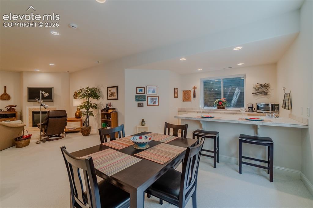 Image 33 of 47: Lower level living space featuring a dining area, wet bar, and fireplace