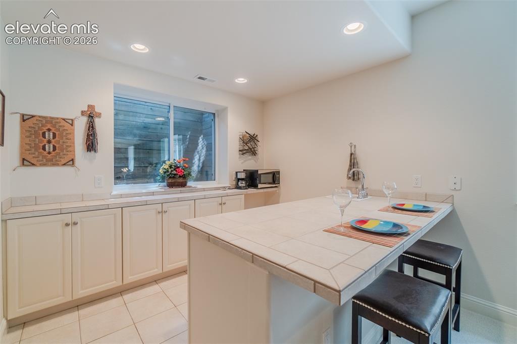 Image 35 of 47: Kitchenette featuring a tile countertop, integrated sink, and recessed ligh