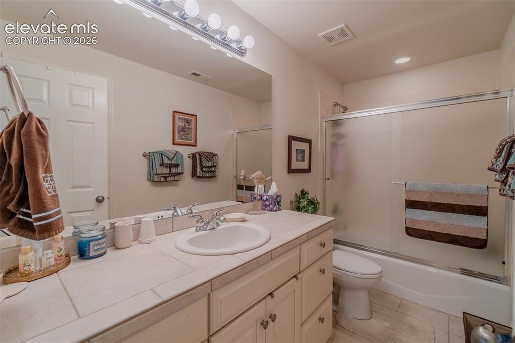 Image 40 of 47: Bathroom featuring a spacious vanity with an integrated sink, tile countert