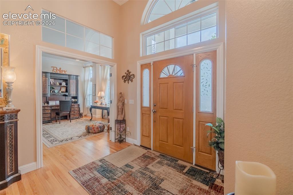 Image 5 of 47: Foyer with hardwood flooring, a tall arched transom window, and a wood entr