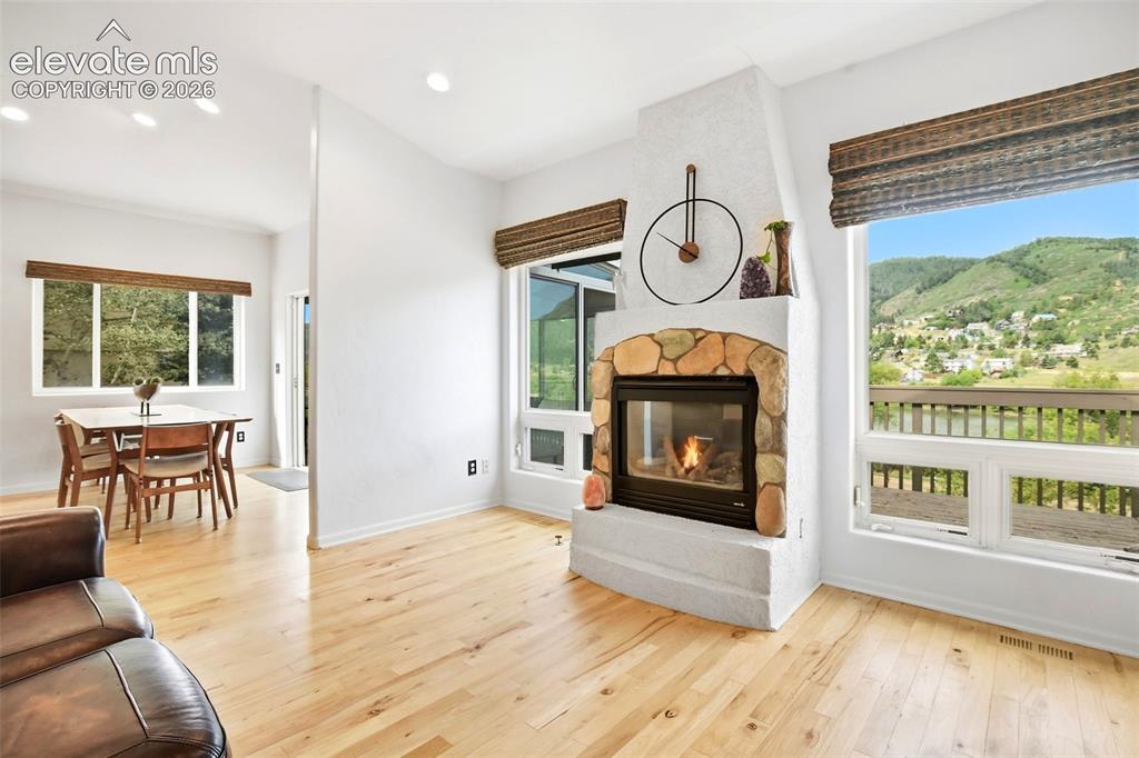 Image 10 of 49: Hardwood flooring, recessed lighting, stone-clad fireplace, large windows,