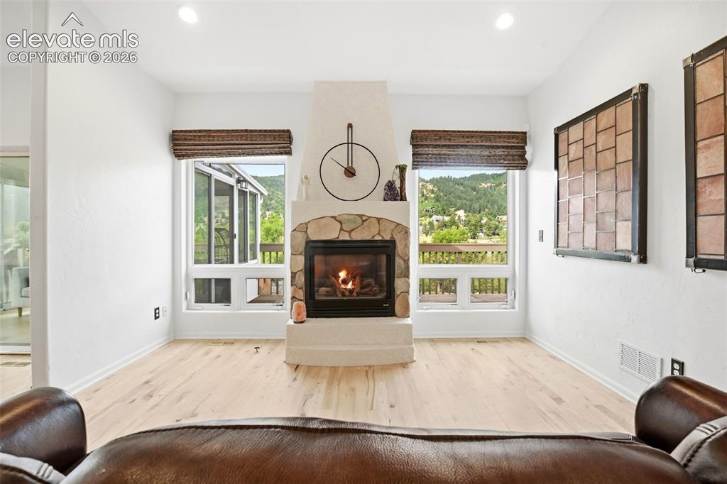 Image 11 of 49: Central fireplace with a stone surround, light wood-finish flooring, recess