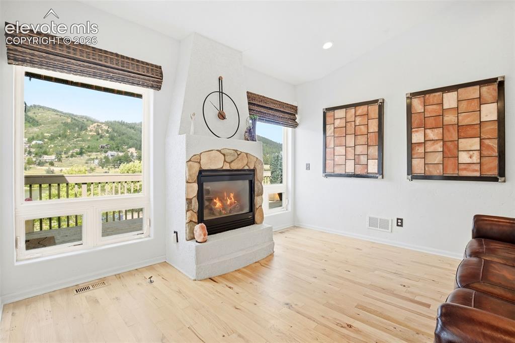 Image 12 of 49: Bright living space featuring light wood-finish flooring, a stone-accented 