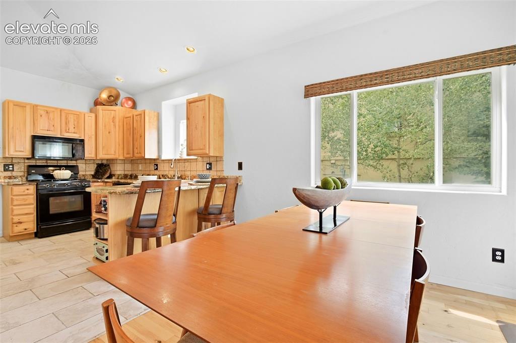 Image 13 of 49: Kitchen featuring wood cabinetry, a black range, tile backsplash, and reces
