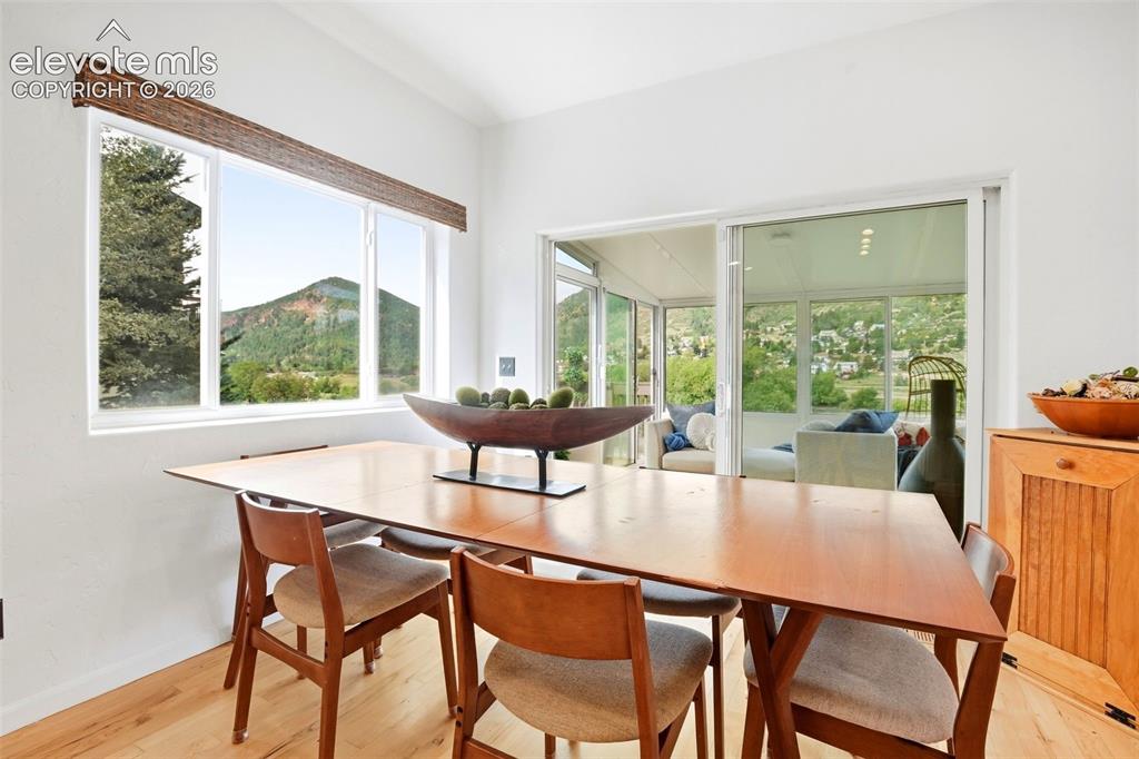 Image 18 of 49: Vaulted ceiling, wood-finish flooring, large window with mountain scenery,