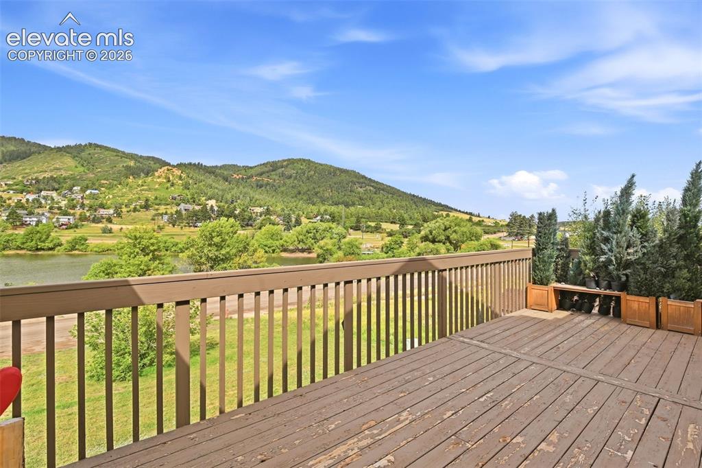Image 22 of 49: Expansive outdoor deck with a wooden railing and a scenic mountain backdrop