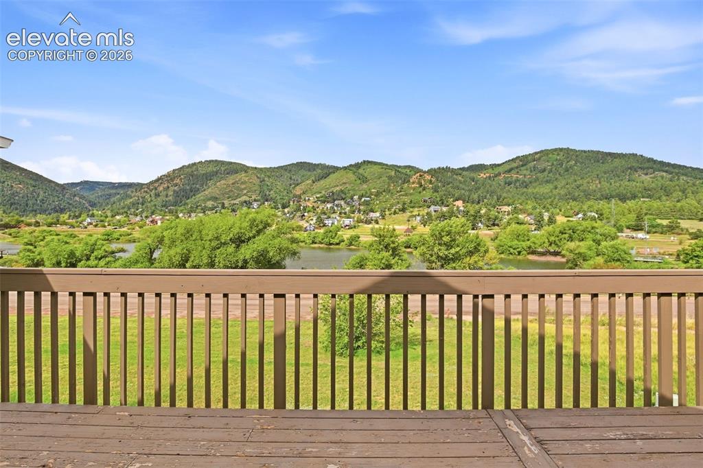 Image 23 of 49: Expansive outdoor deck with wood-finish flooring and railing, overlooking a