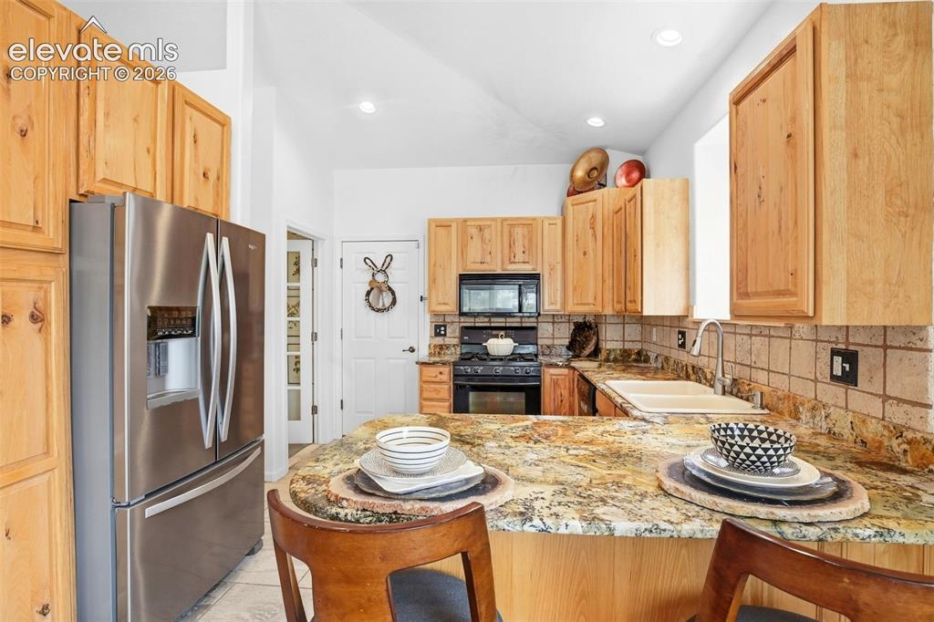 Image 28 of 49: Kitchen featuring light wood cabinetry, granite countertops, stainless stee