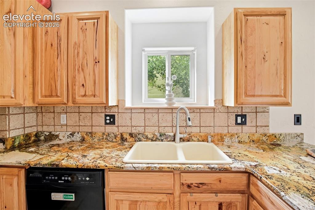 Image 30 of 49: Light wood cabinetry with paneling, granite countertops, tile backsplash, a