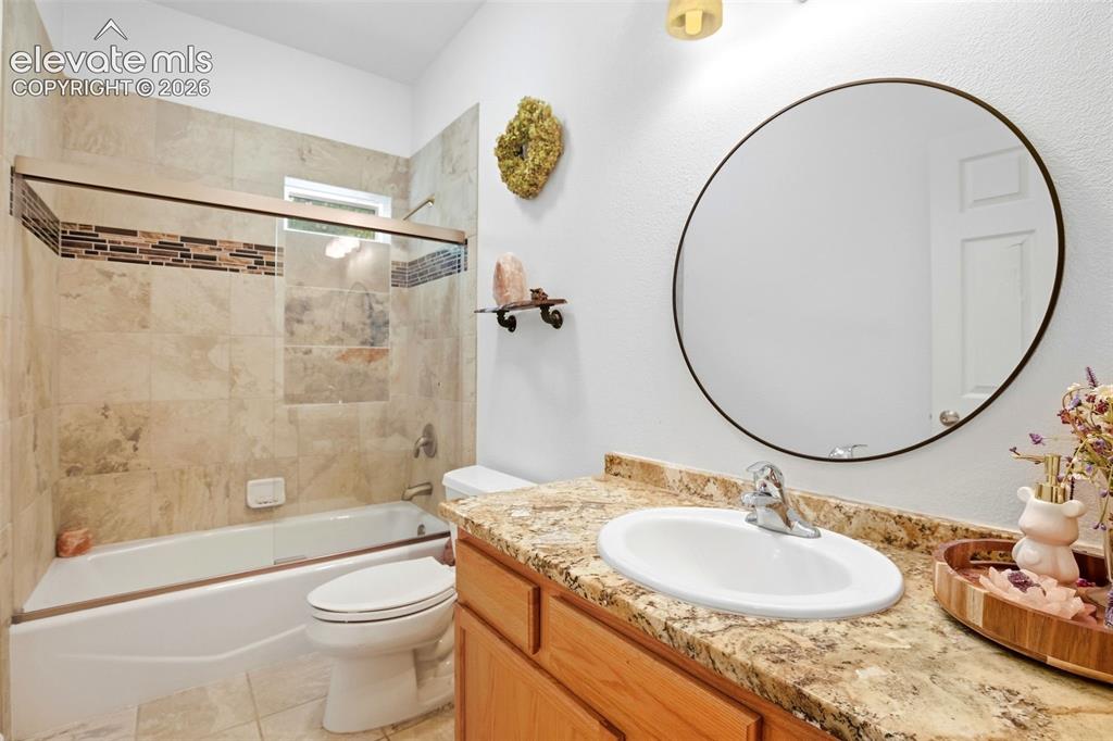 Image 34 of 49: Bathtub with tiled surround, mosaic accent tile, and sliding glass enclosur