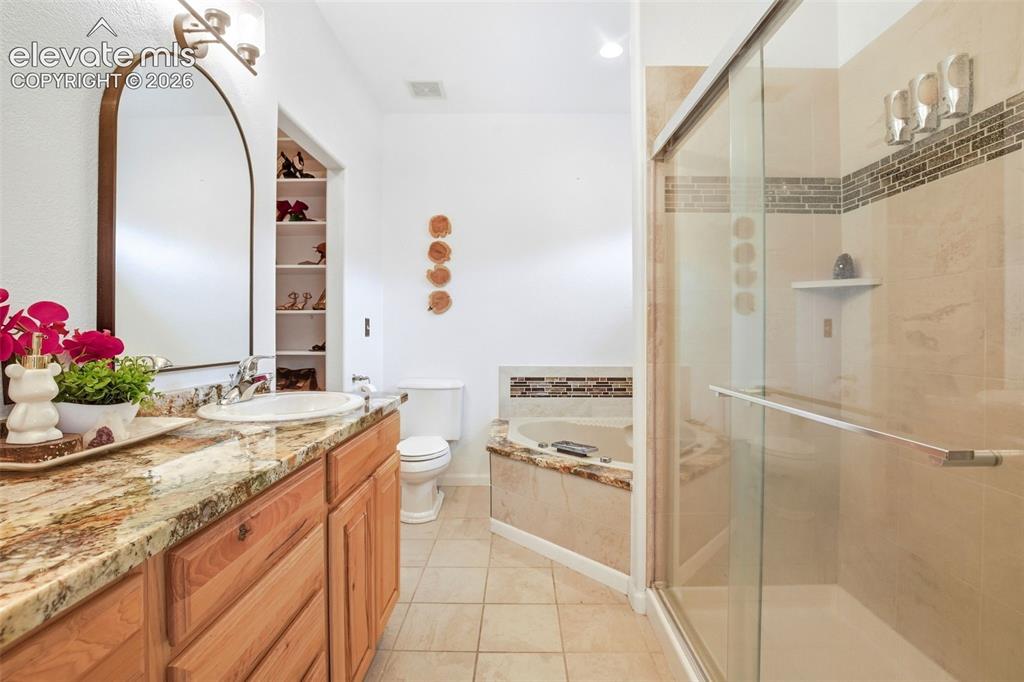Image 39 of 49: Dual vanity with granite countertop, built-in shelving, corner soaking tub,