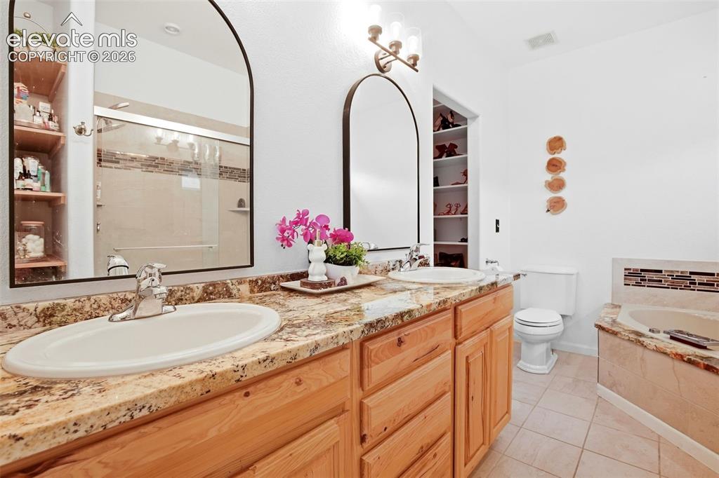 Image 40 of 49: Dual vanity with wood-finish cabinetry and light-toned countertops