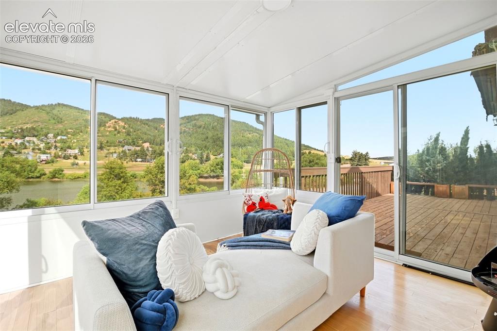 Image 7 of 49: Sunroom with walls of windows and sliding glass door walks out to to an ext