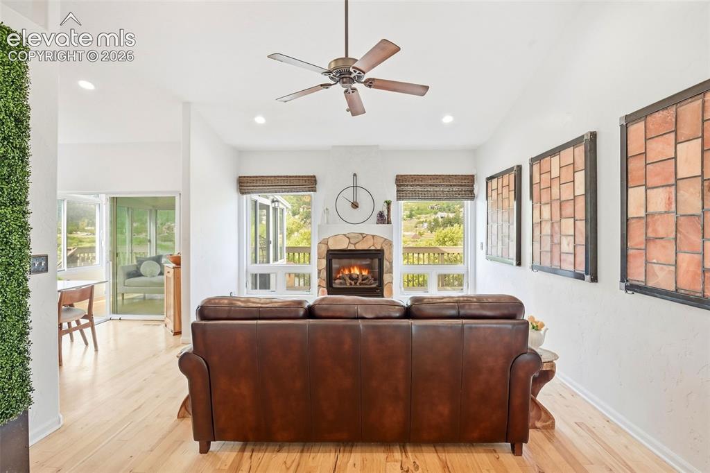 Image 8 of 49: Living room with hickory flooring, custom art work, and a gas log stone-sur