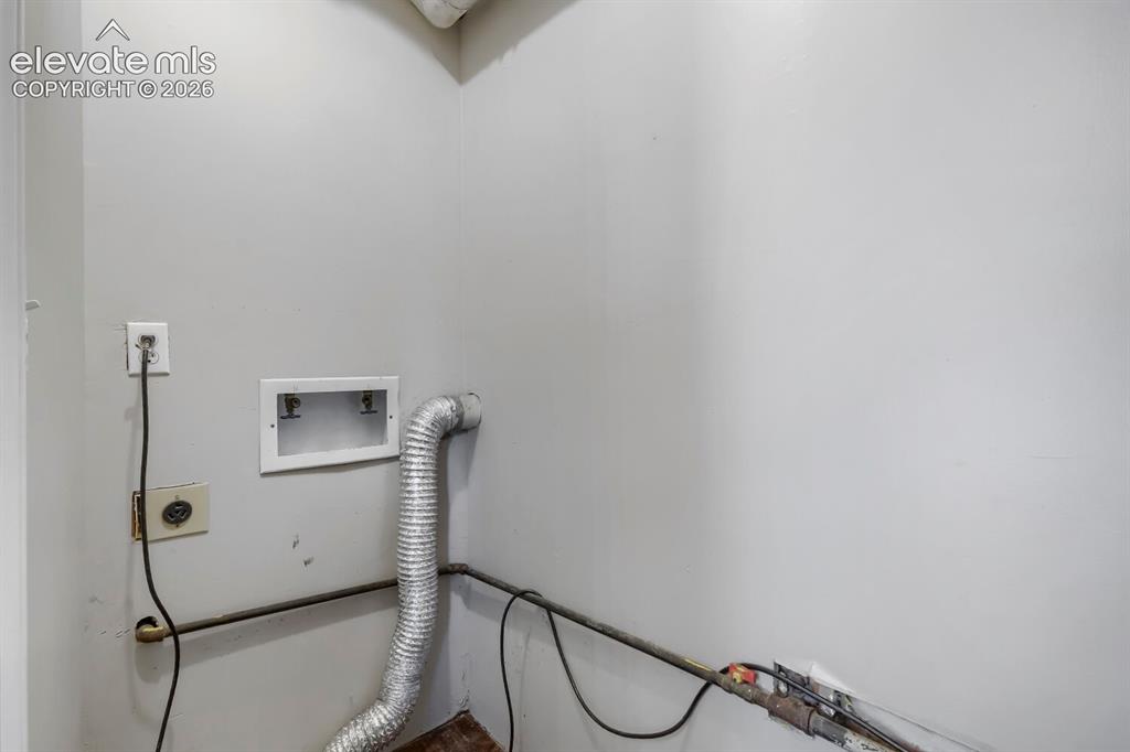 Image 11 of 28: Utility space featuring light gray walls, an electrical outlet, and a dryer