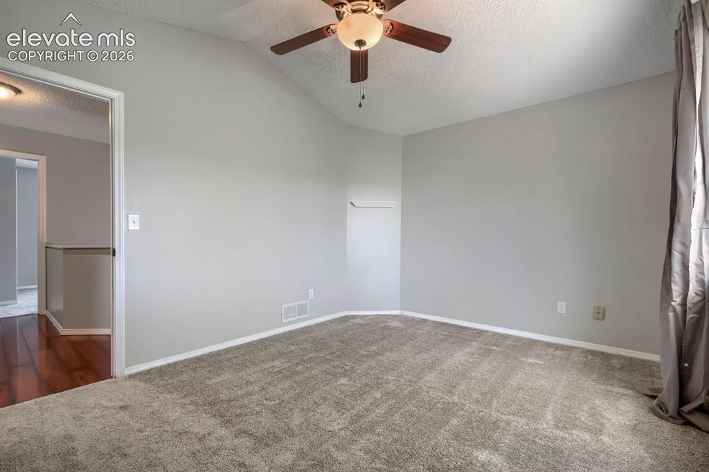 Image 15 of 28: Vaulted ceiling room with ceiling fan light fixture, gray carpet flooring,