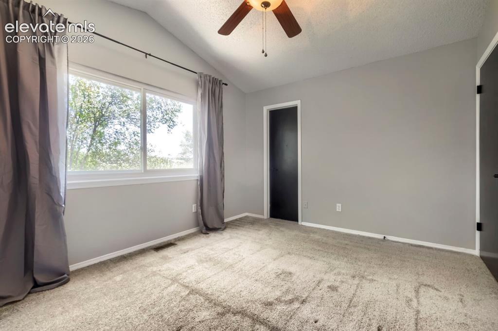 Image 16 of 28: Vaulted ceiling room with ceiling fan light fixture, gray carpet flooring,