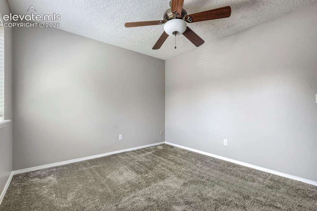 Image 17 of 28: Vaulted ceiling room with ceiling fan light fixture, gray carpet flooring,