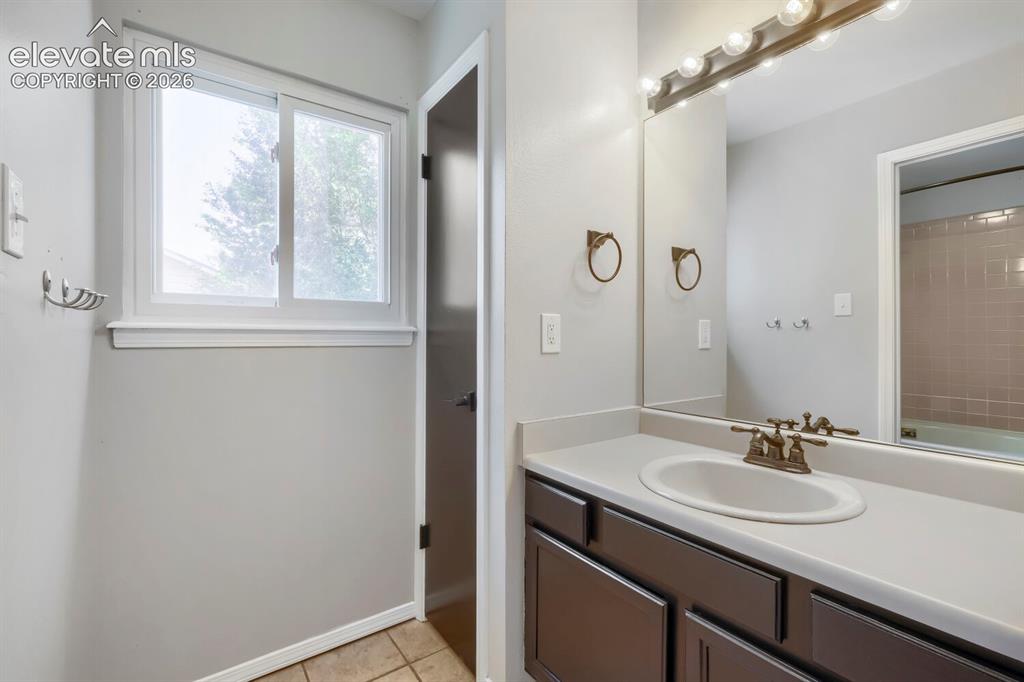 Image 18 of 28: Bathroom vanity featuring an integrated sink, broad mirror, and overhead li