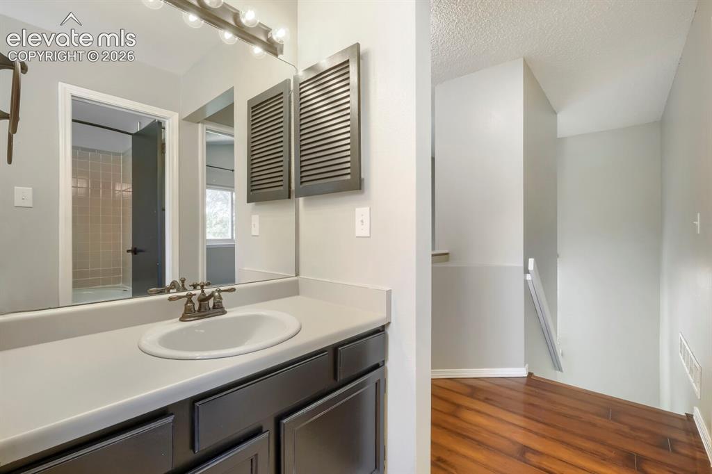 Image 20 of 28: Bathroom vanity featuring a single basin sink, dual-handle faucet, and inte