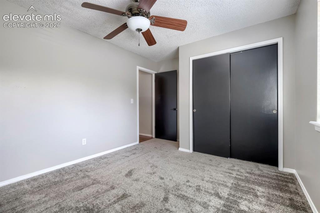 Image 22 of 28: Neutral gray walls with white trim, gray carpet flooring, and a ceiling fan