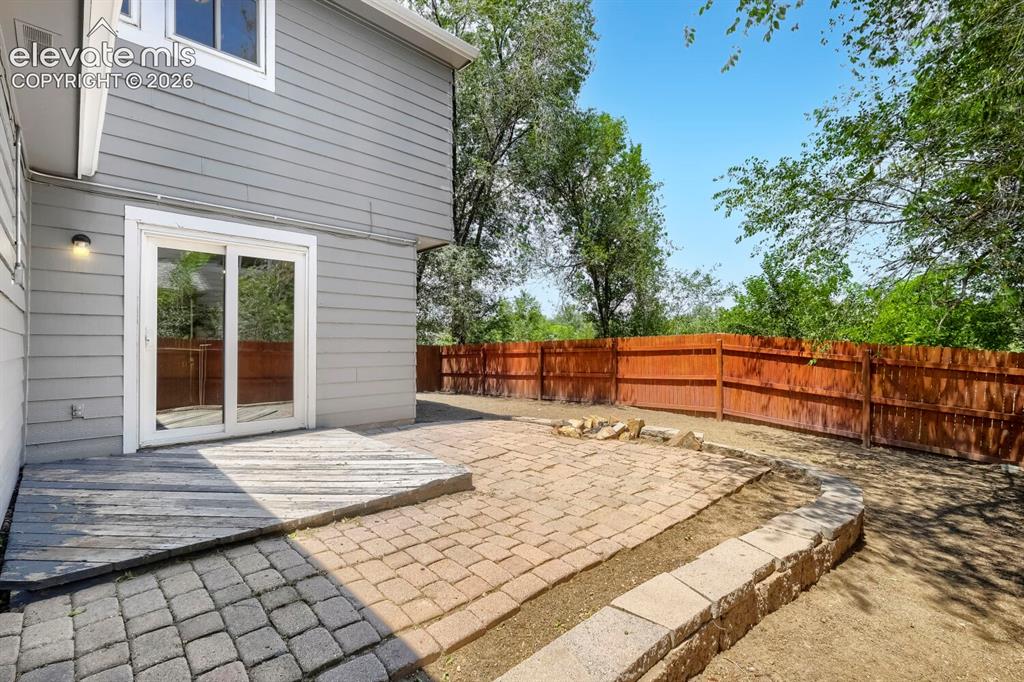 Image 25 of 28: Private outdoor living space with sliding glass doors, a wood deck, a paver