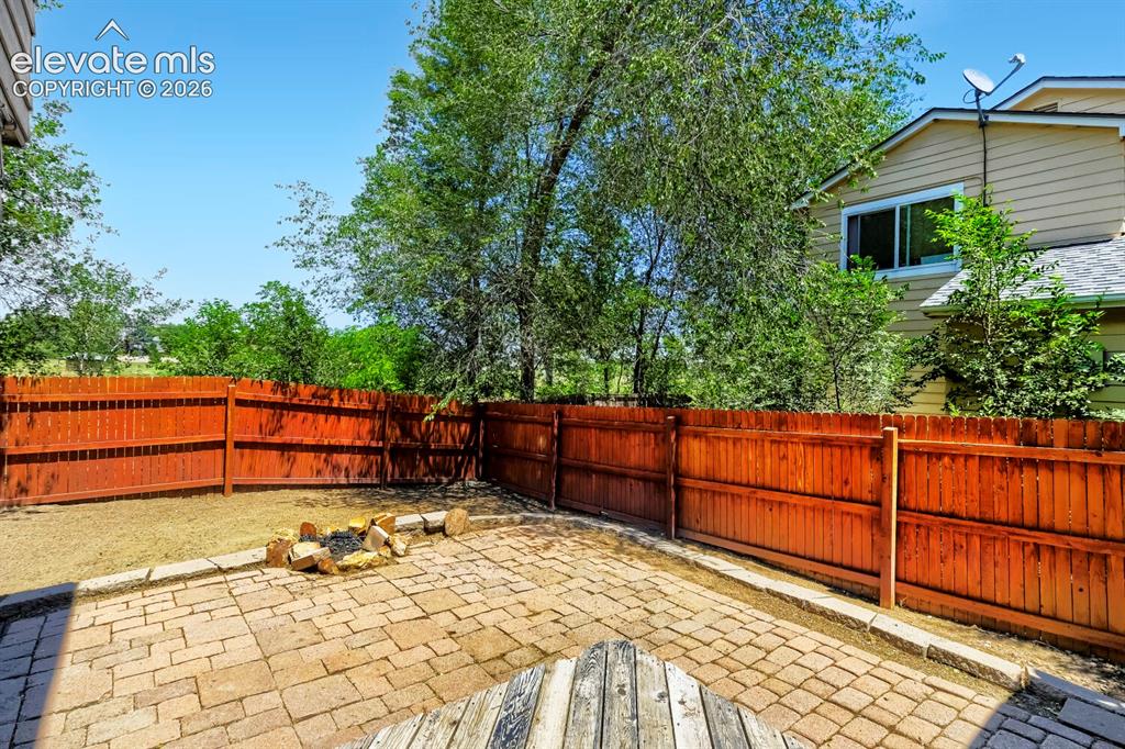 Image 26 of 28: Expansive backyard featuring a paver patio with a stone fire pit, wood priv
