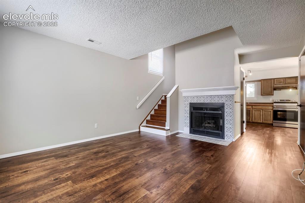 Image 3 of 28: Living area featuring wood-finish flooring, a fireplace with decorative til