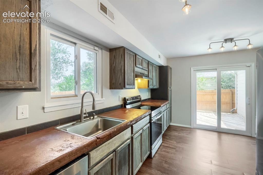 Image 7 of 28: Kitchen featuring wood-finish flooring, dark wood cabinetry, a stainless st
