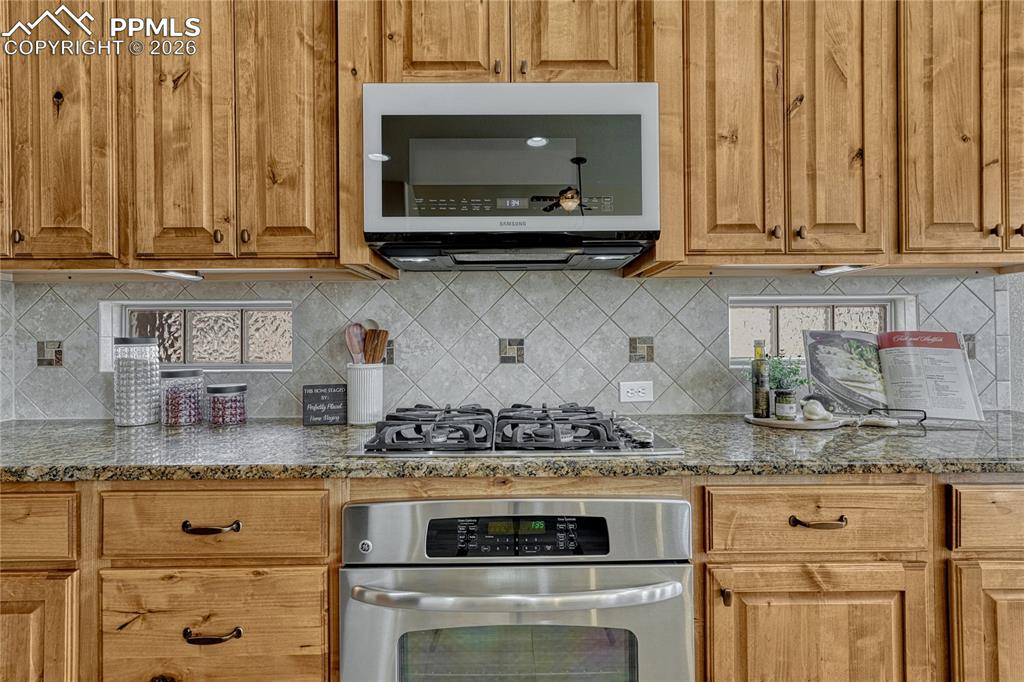 Image 20 of 50: Cooking is a joy with the premium gas stove, custom tile backsplash, and be