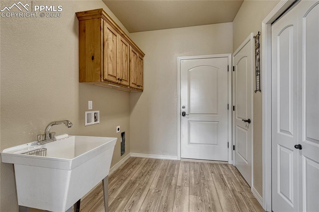 Image 24 of 50: The dedicated main-level laundry room features a convenient utility sink, k