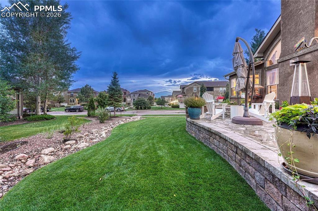 Image 43 of 50: The landscaping features lush green grass, beautiful rock borders, and matu