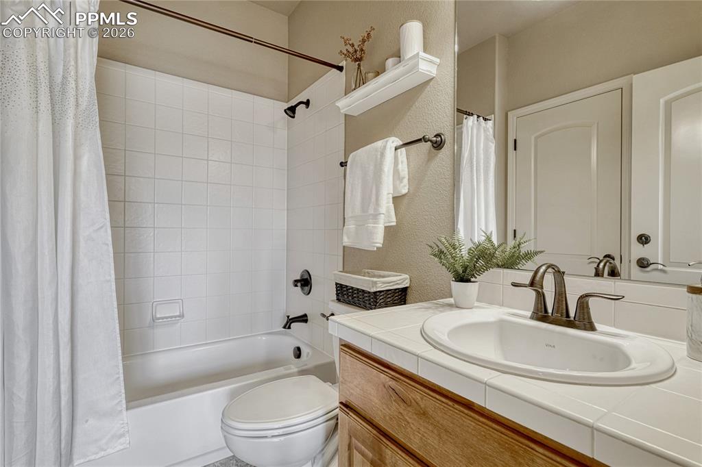 Image 6 of 50: This convenient main-level full bathroom features a white tiled vanity and 