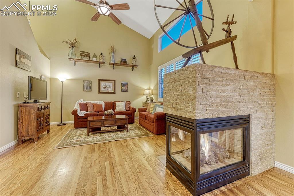 Image 25 of 46: Soaring ceilings, 3 sided stone fireplace and beautiful hardwood flooring