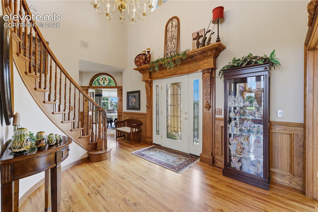 Image 10 of 49: Grand entry with a curved staircase, hardwood flooring, detailed wood wains